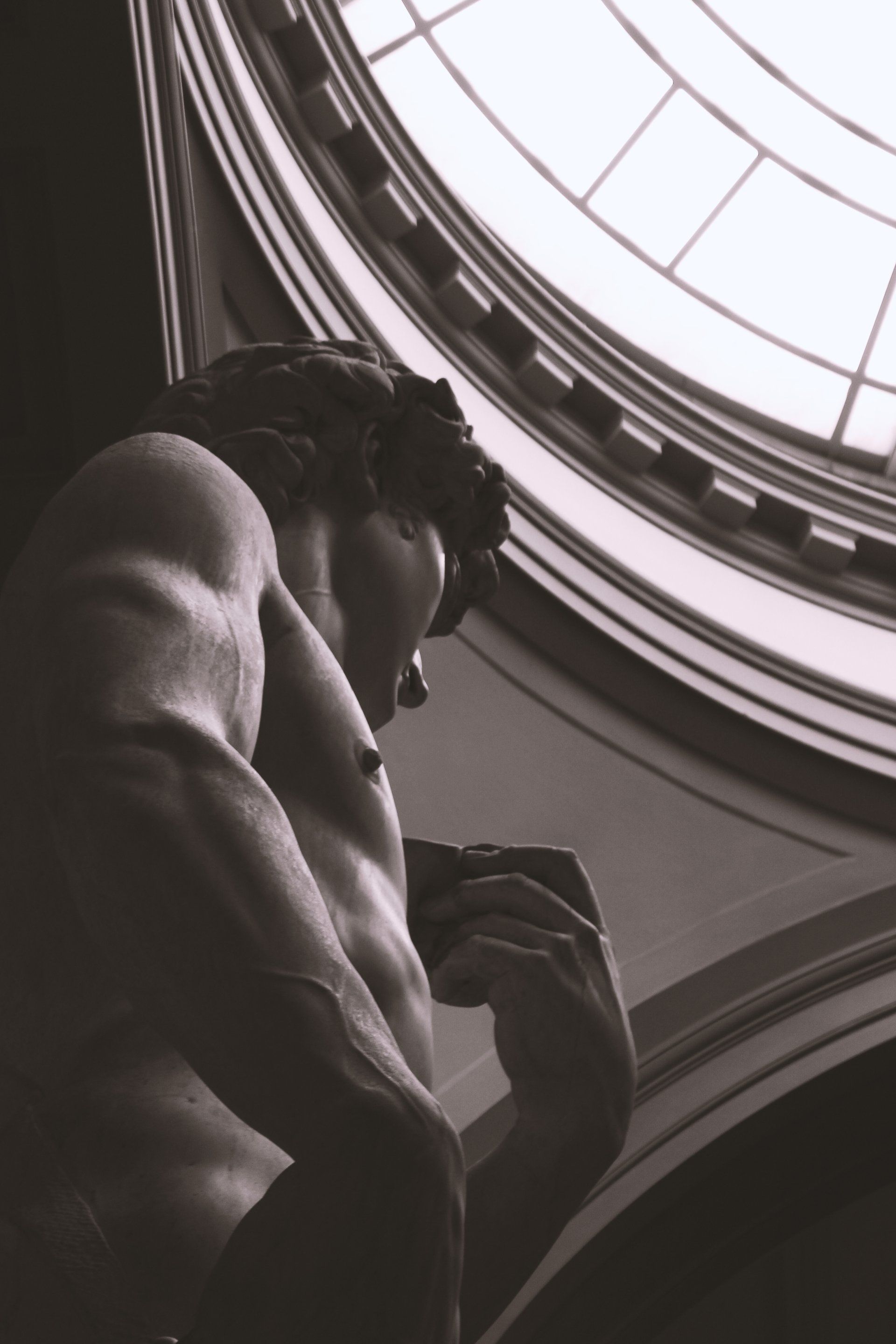 A black and white photo of a statue in front of a window
