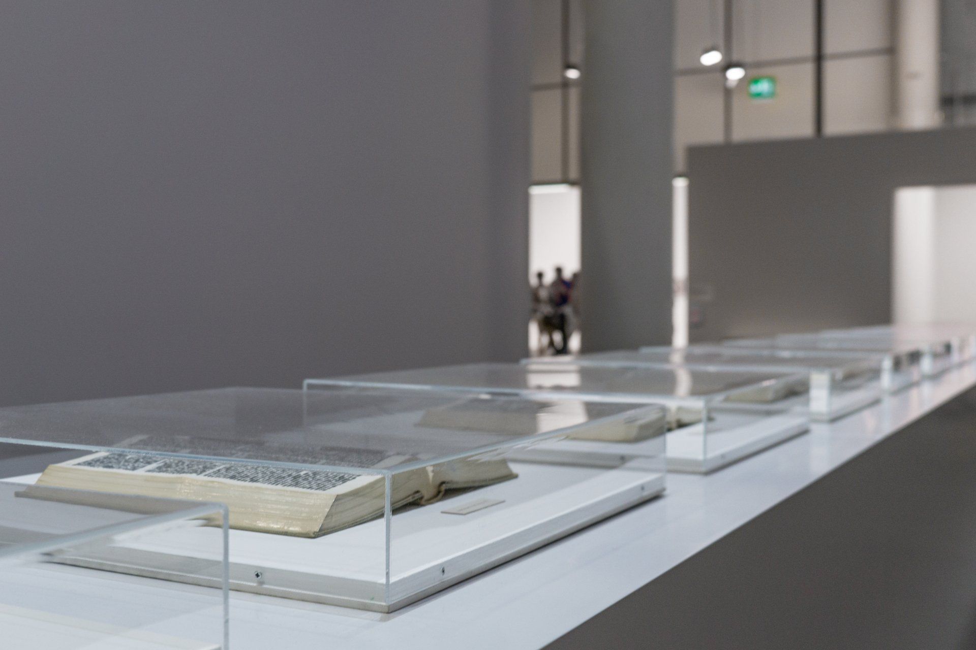 A row of books sitting on top of a table in a glass case.