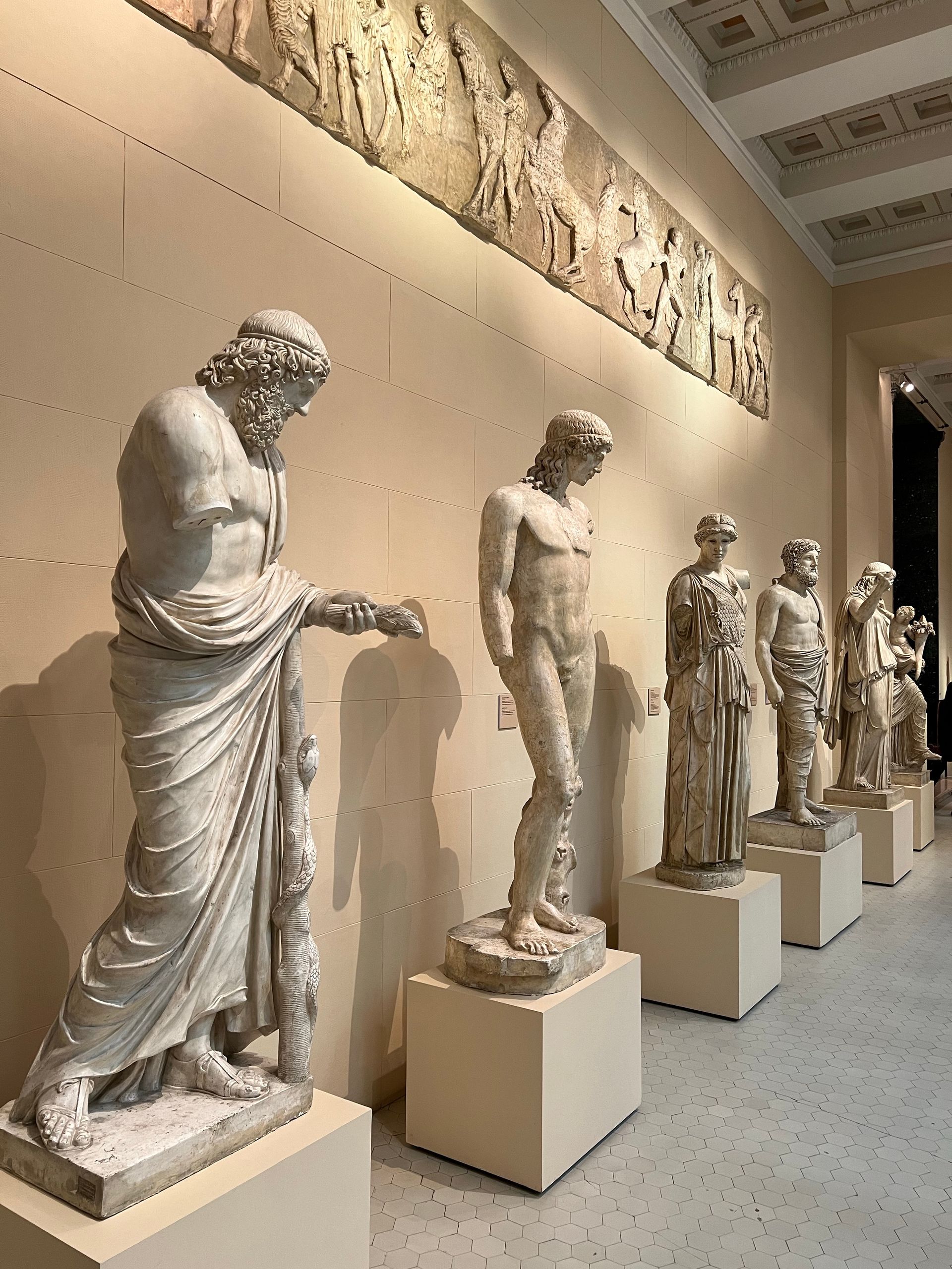 A row of statues are on display in a museum.