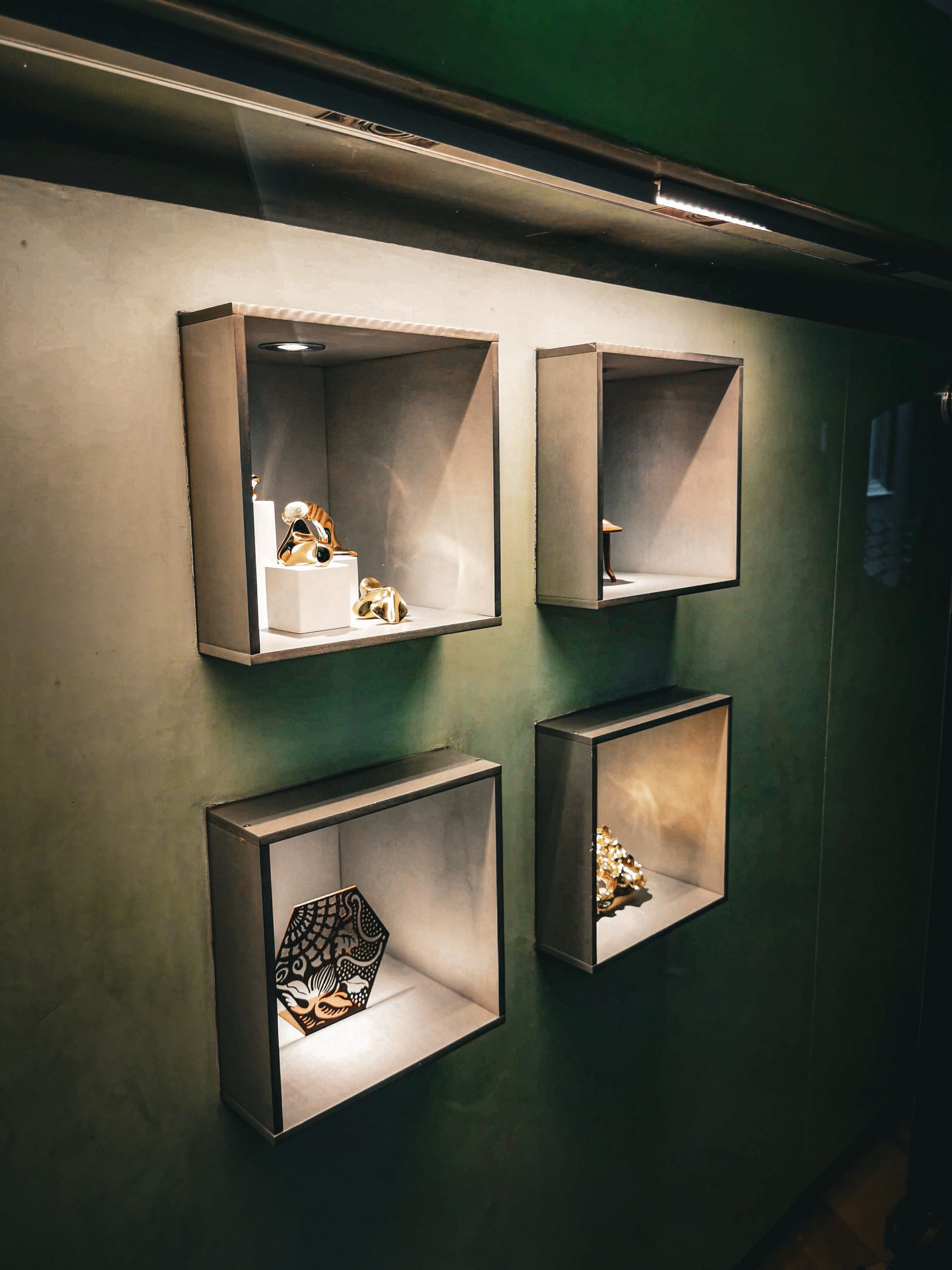 A wall with three shelves filled with objects on it.