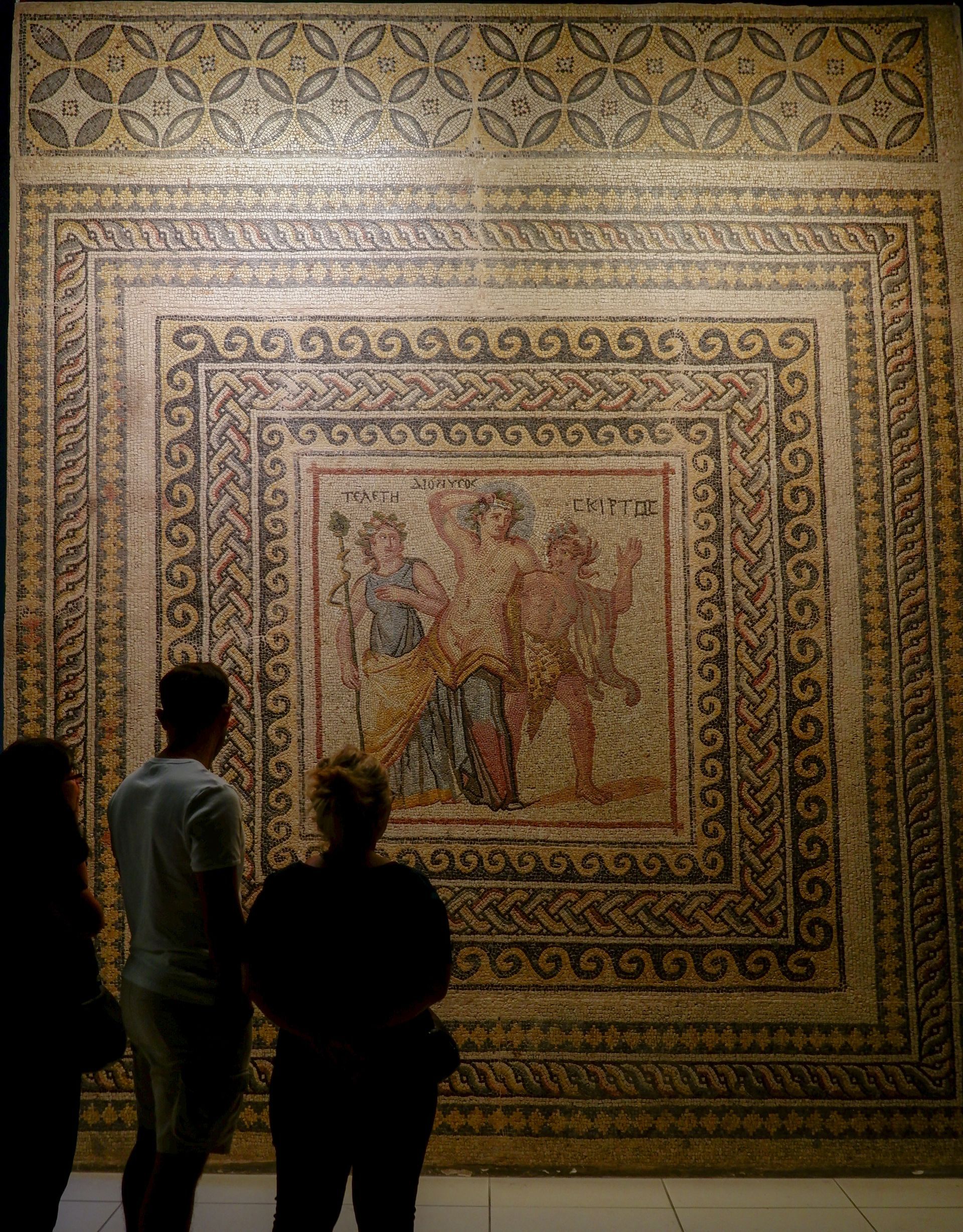 A group of people standing in front of a large mosaic