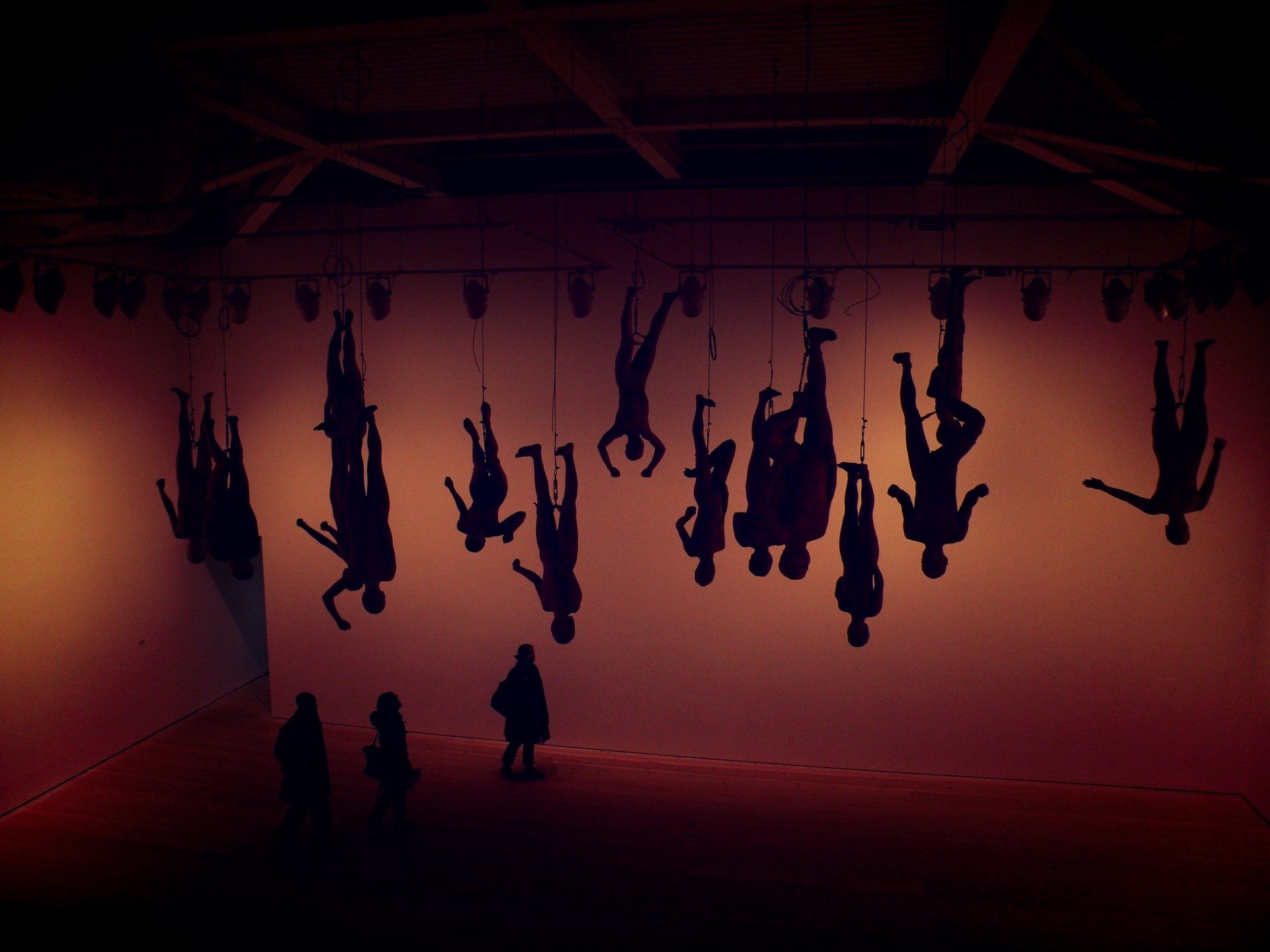 Silhouettes of people hanging upside down on a wall