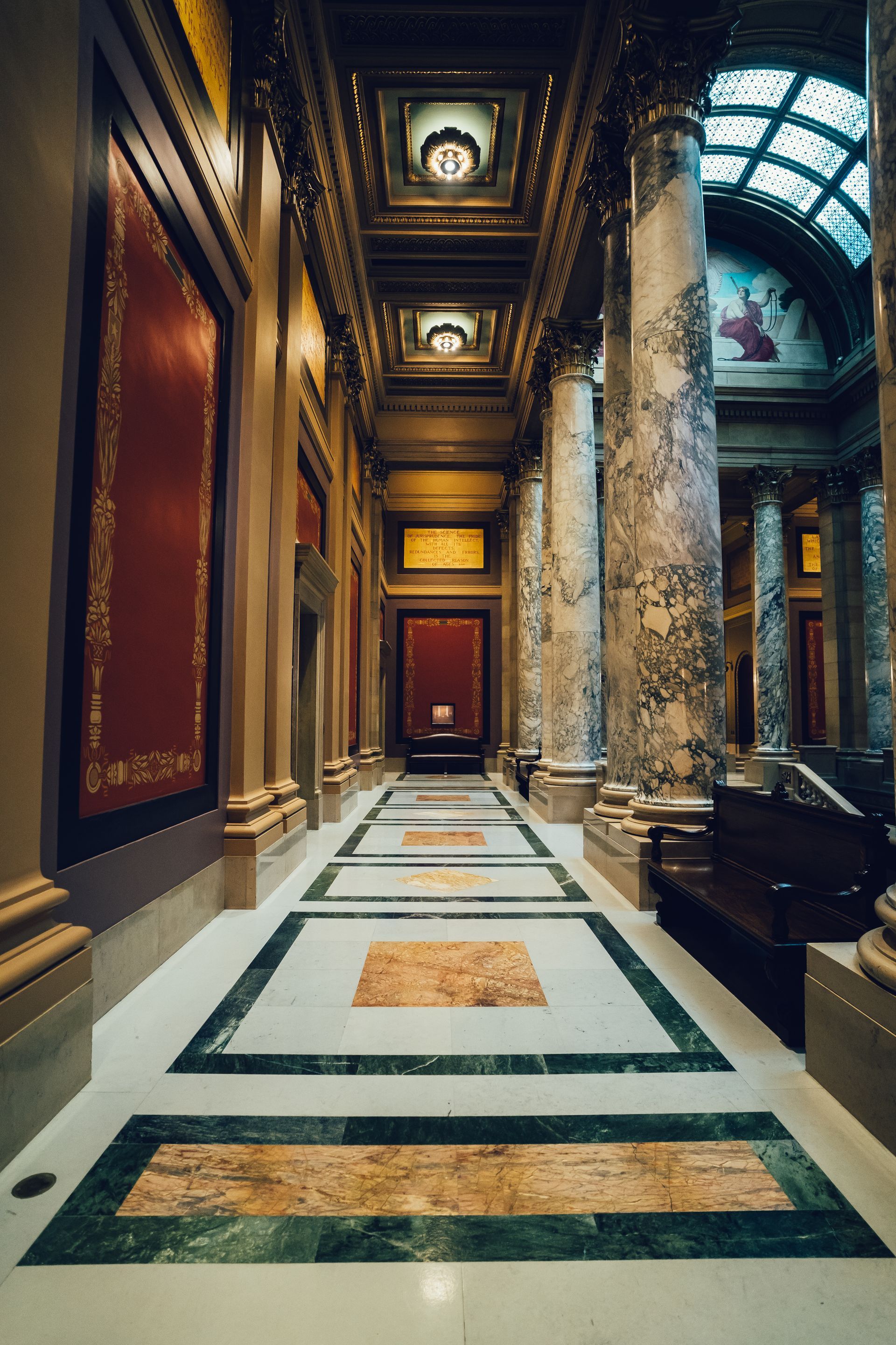 A long hallway in a building with columns and marble floors.