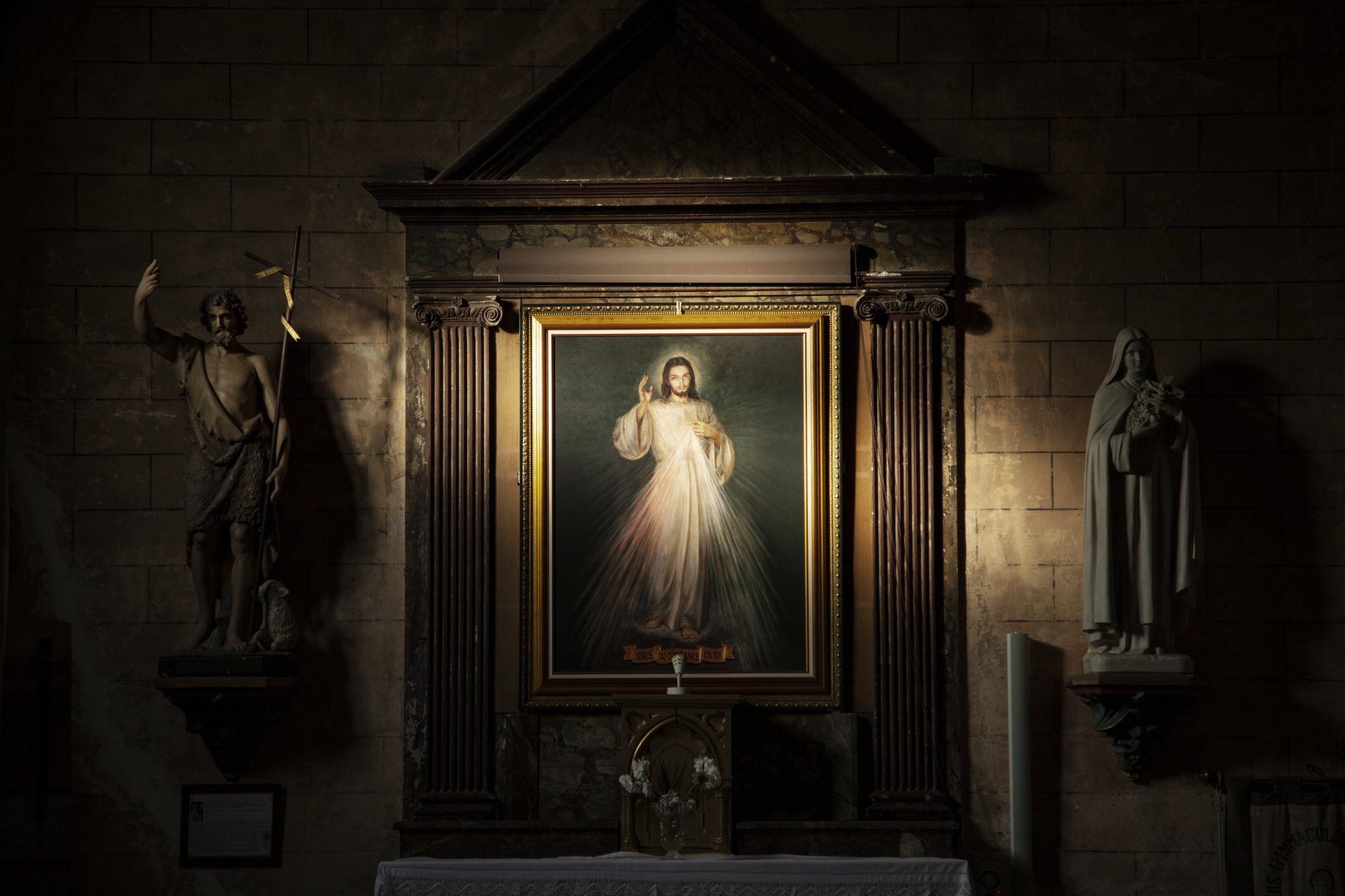 A painting of jesus is hanging on a wall in a church.