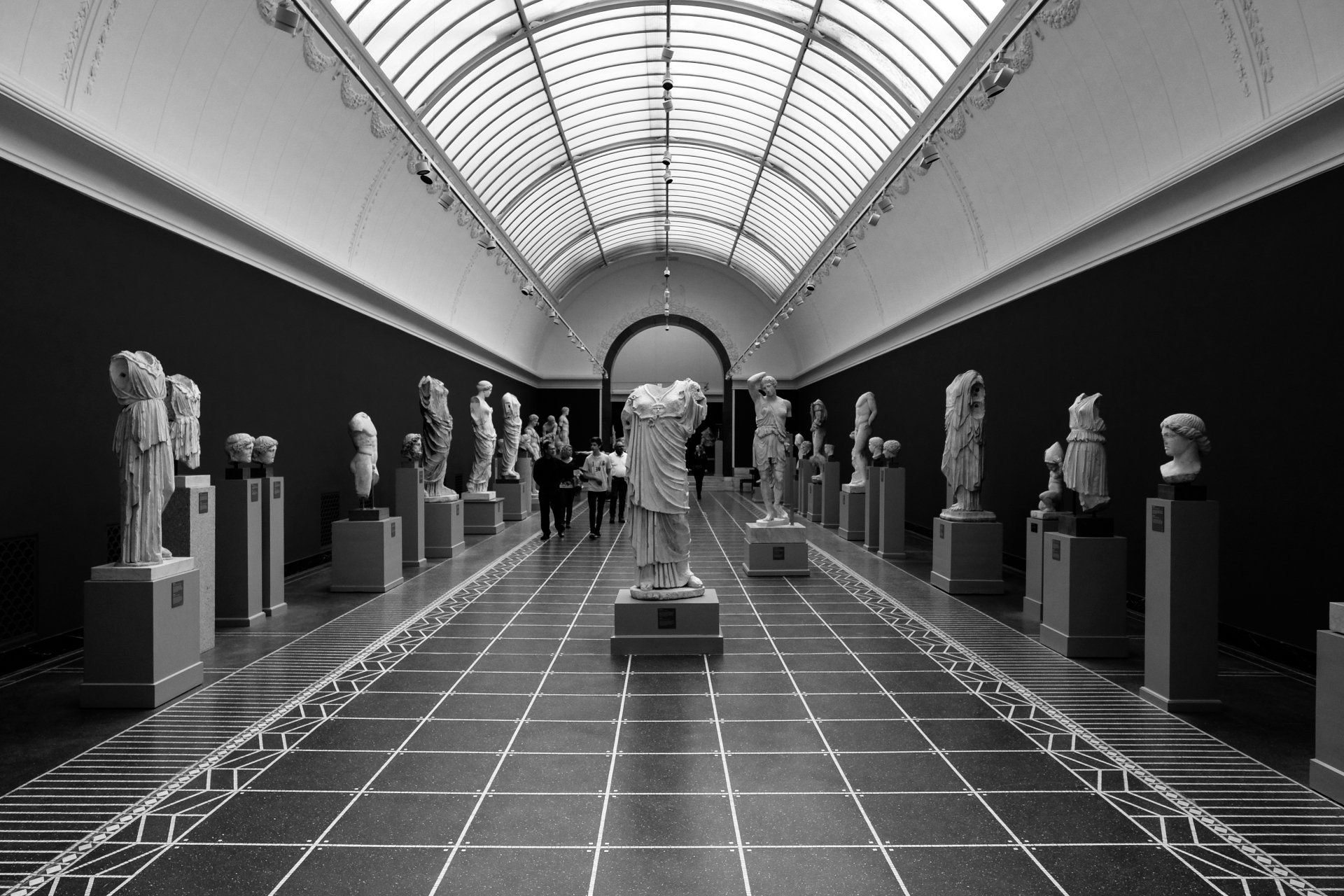 A black and white photo of a museum filled with statues