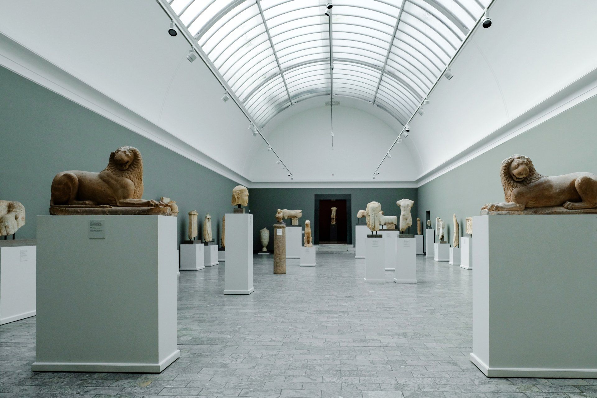 A museum filled with lots of statues including a statue of a lion