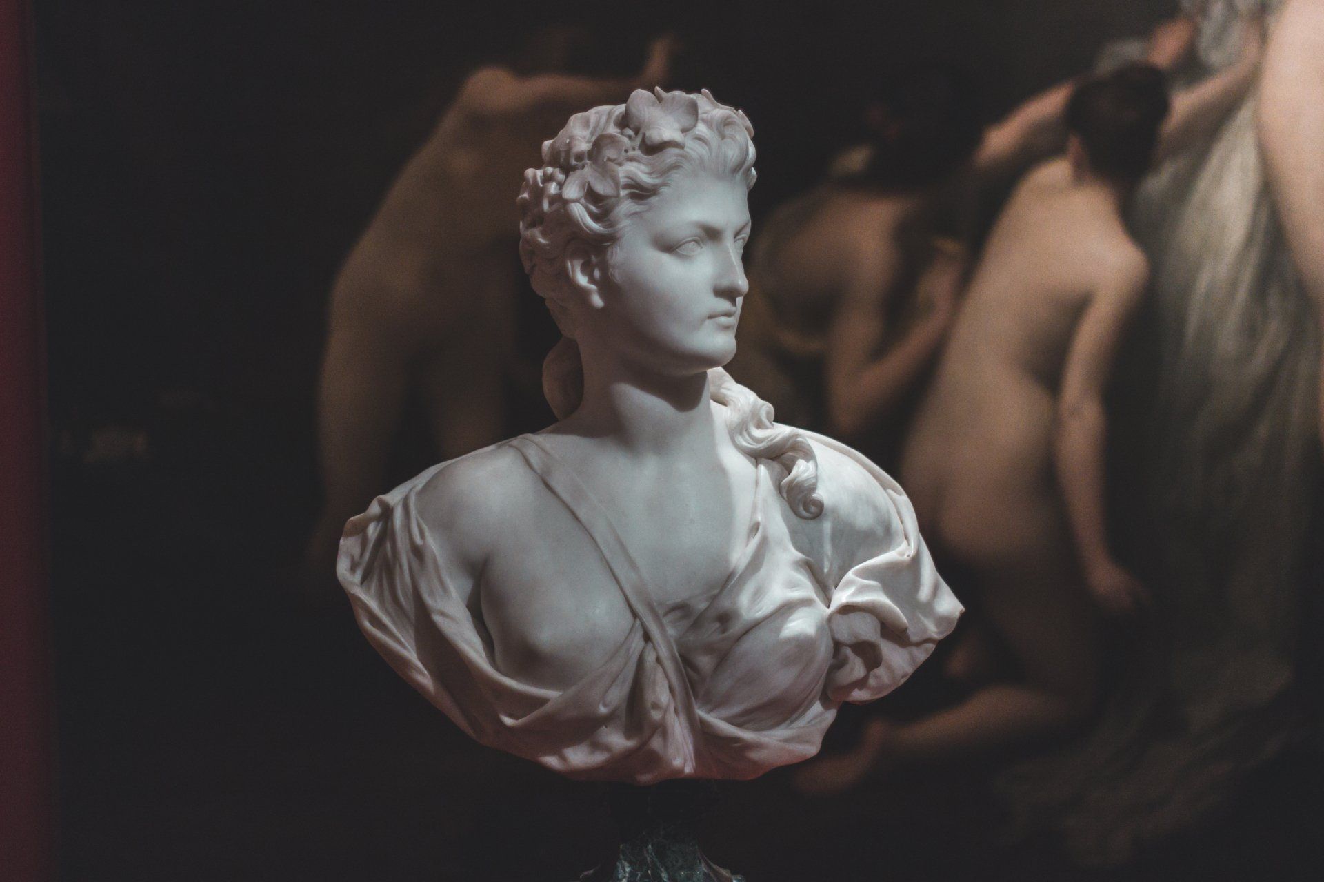 A statue of a woman with a painting in the background.