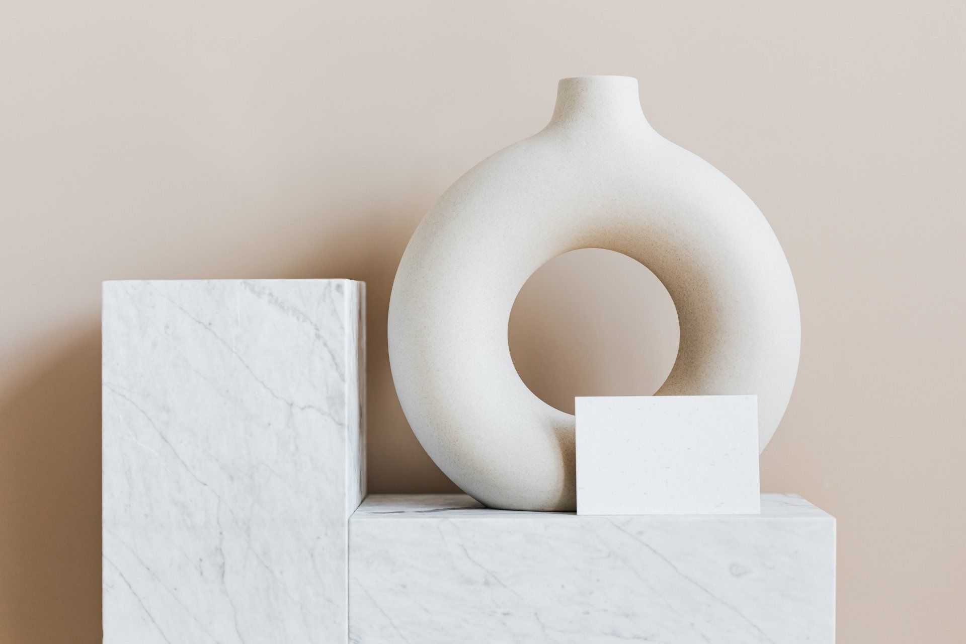A white vase is sitting on top of a white marble block.