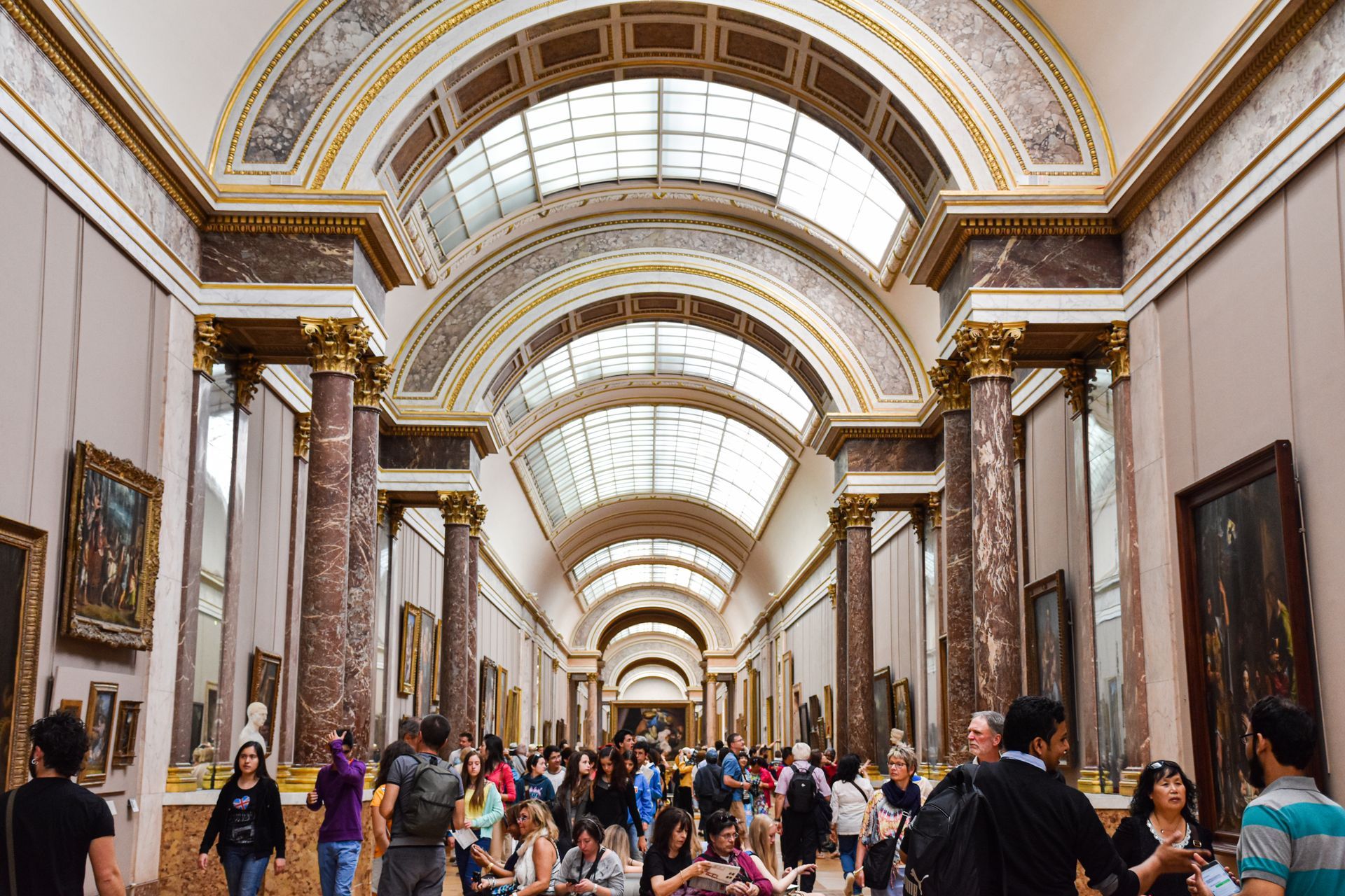 A group of people are walking through a long hallway in a museum.