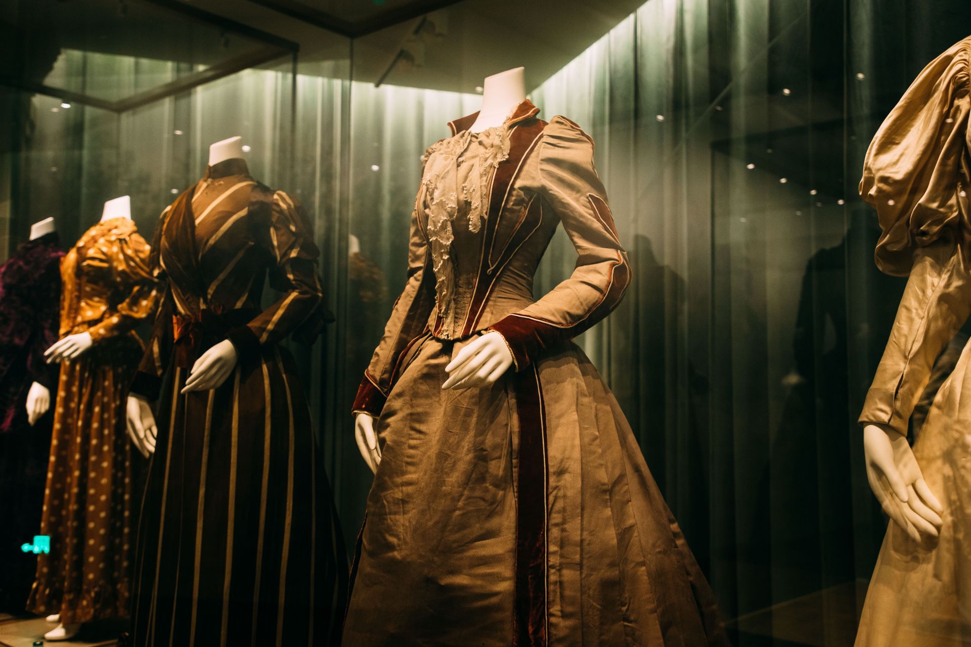 A row of mannequins wearing dresses in a museum.