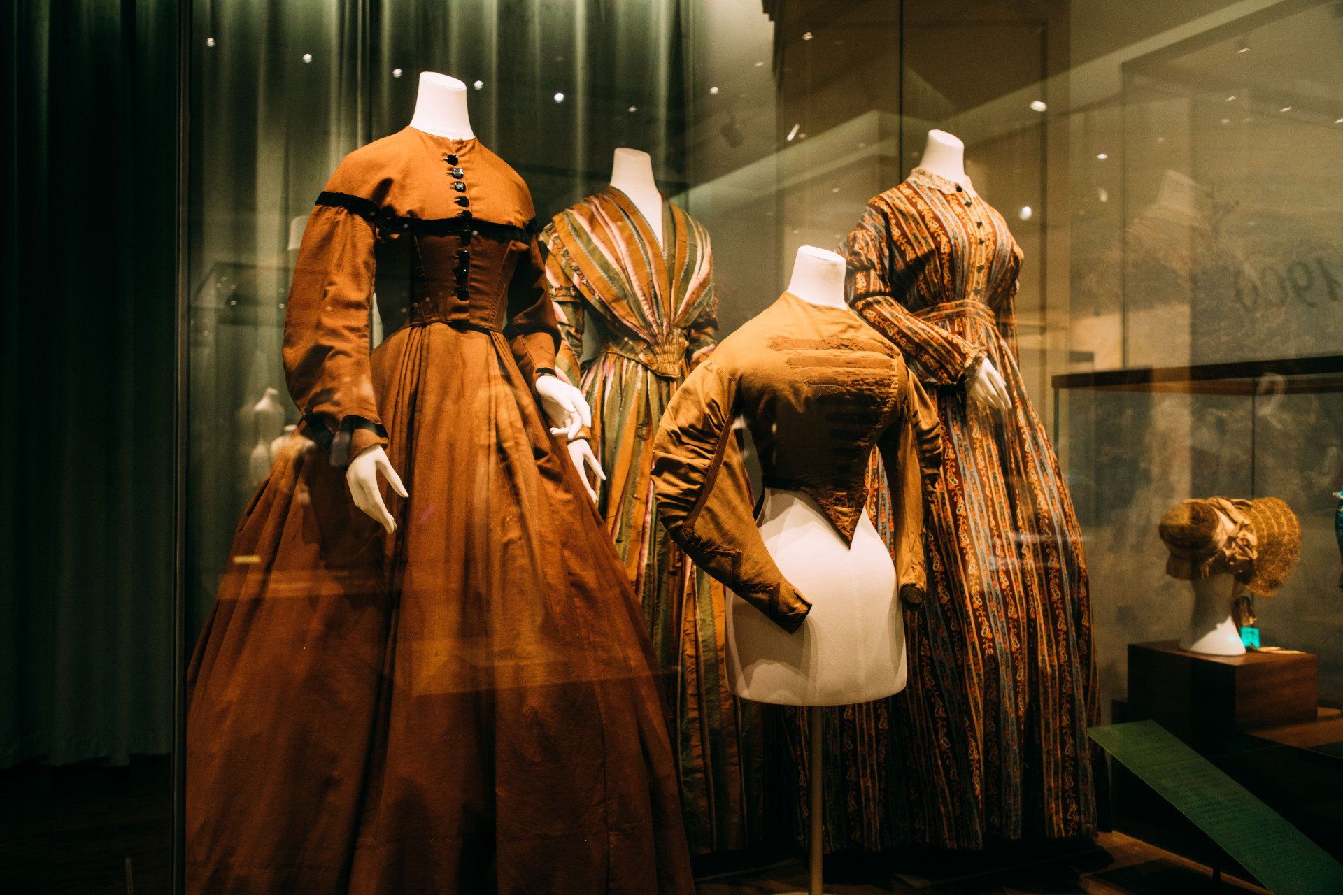A group of dresses on mannequins in a museum.