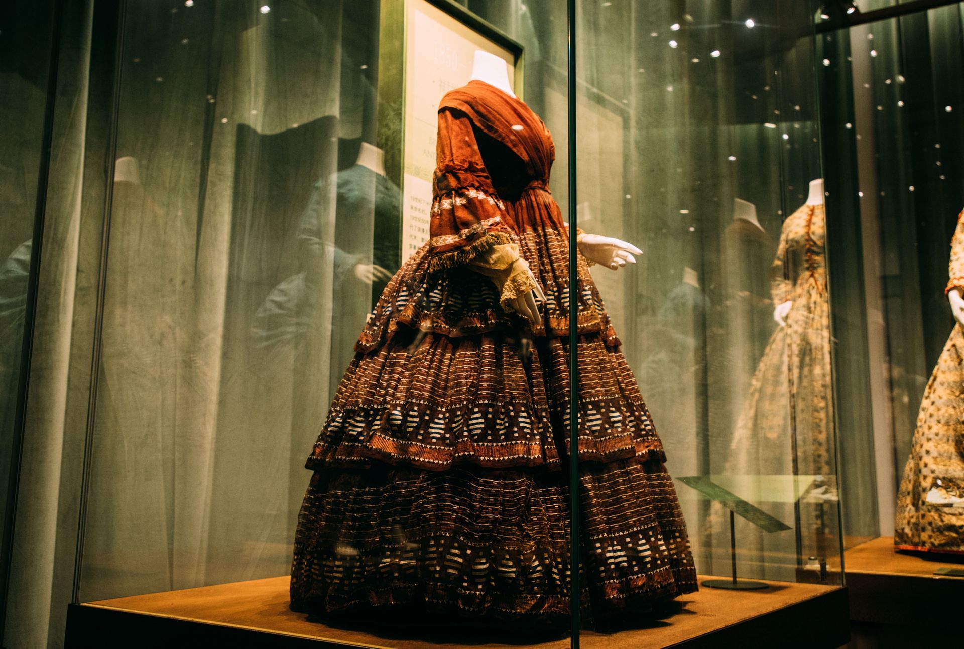 A dress is on display in a glass case in a museum.