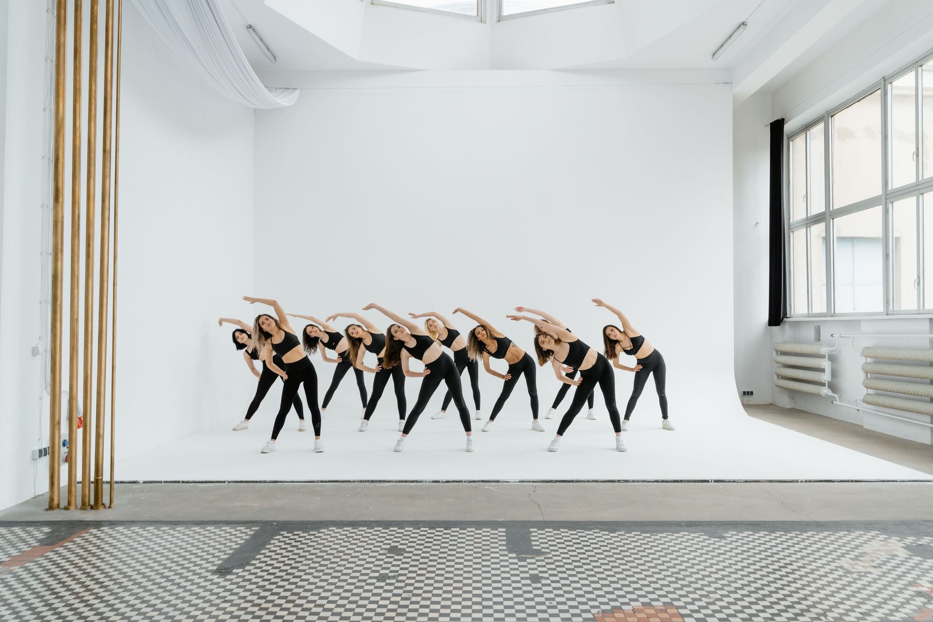 A group of dancers are dancing in a white room.